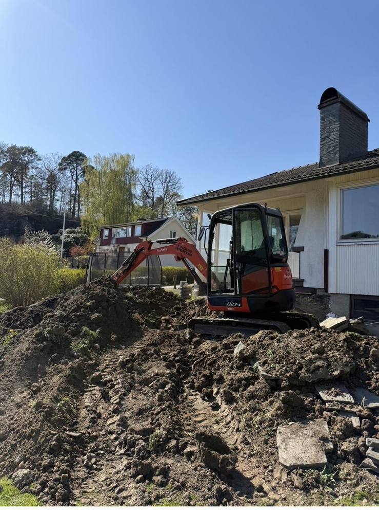 Grävmaskin vid husgrund under schaktning